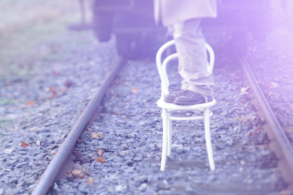 Muž stojící na židli na vlakové trati